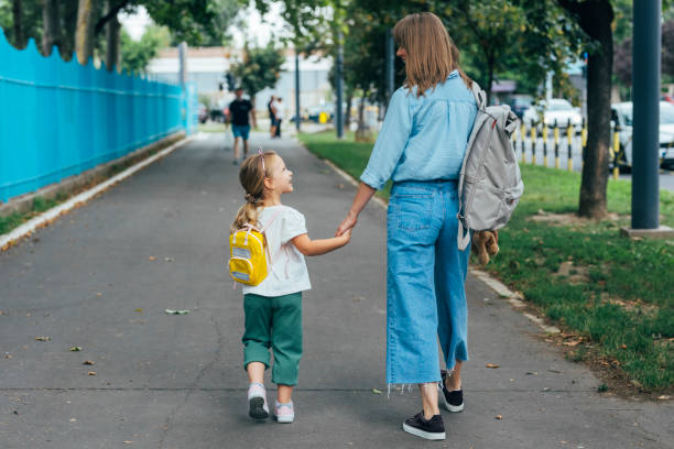 Mama și fiica ei mergând împreună spre școală